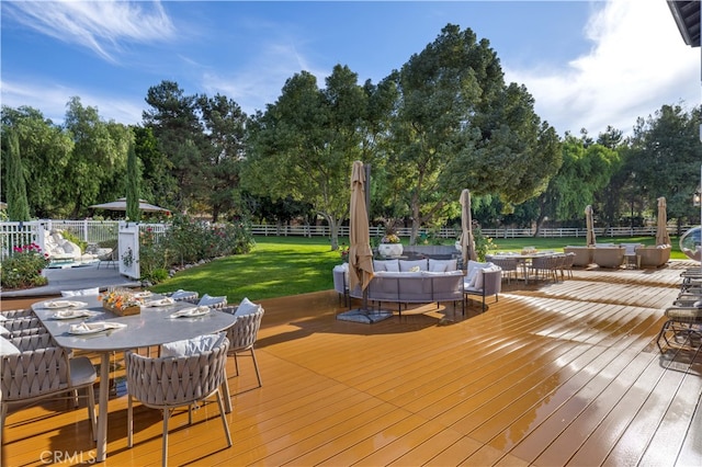 wooden terrace with a yard, outdoor dining space, fence, and an outdoor hangout area