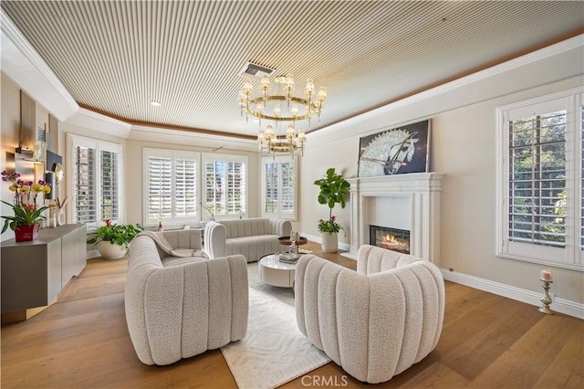 living room with plenty of natural light, crown molding, wood finished floors, and a glass covered fireplace