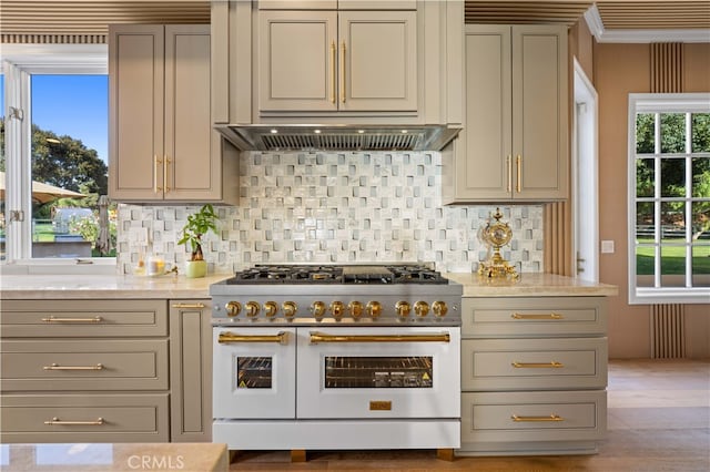 kitchen featuring range with two ovens, extractor fan, light stone counters, and tasteful backsplash