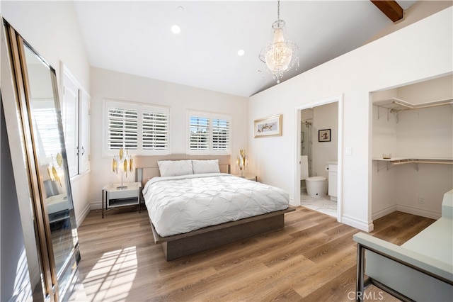 bedroom with baseboards, lofted ceiling, ensuite bathroom, an inviting chandelier, and light wood-style floors