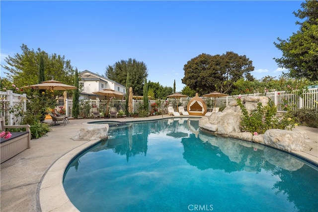 view of swimming pool with a pool with connected hot tub, fence, and a patio