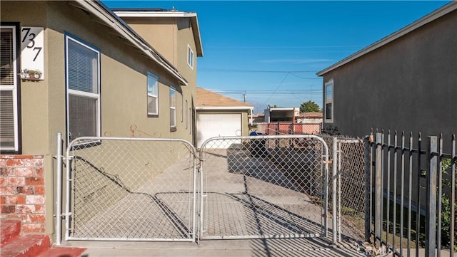 exterior space with a gate, fence, and stucco siding