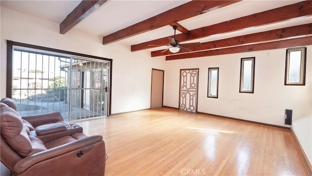 living area with beamed ceiling, light wood-style flooring, and baseboards