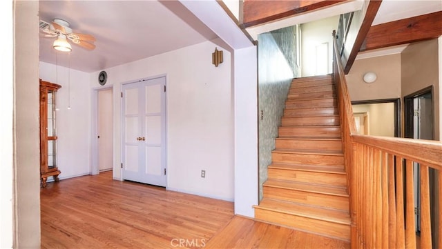 staircase with wood finished floors, a ceiling fan, and baseboards