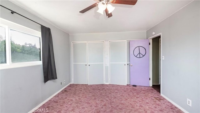 unfurnished bedroom featuring carpet flooring, ceiling fan, baseboards, and two closets