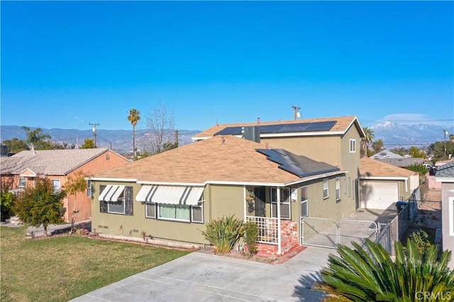 view of front of home featuring a gate, a mountain view, a front lawn, and stucco siding