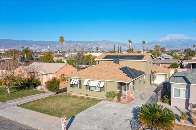 single story home featuring a mountain view, solar panels, a gate, stucco siding, and a front yard