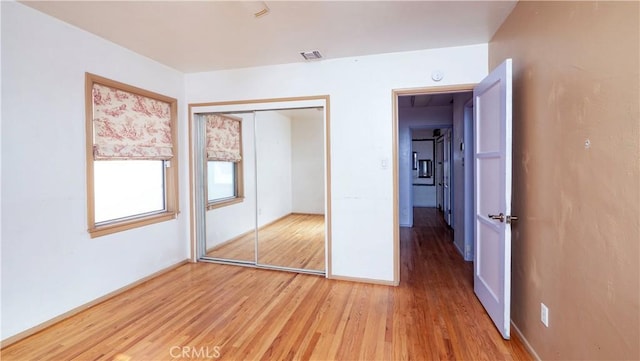 unfurnished bedroom with light wood finished floors, a closet, and visible vents