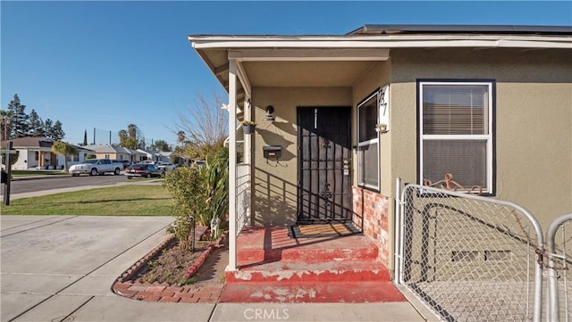 property entrance with a gate, a residential view, and stucco siding