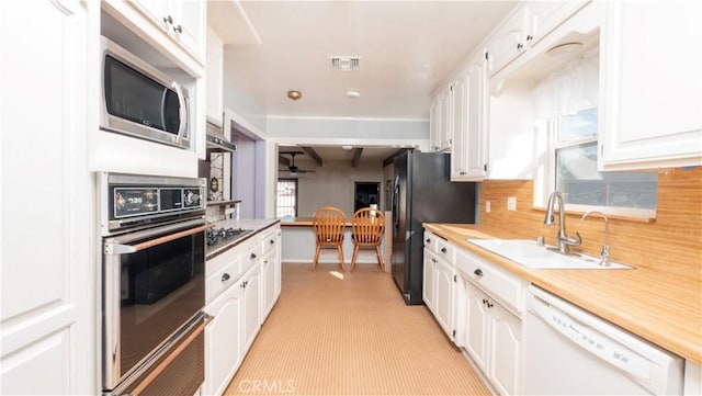 kitchen with a sink, visible vents, white cabinets, light countertops, and black appliances