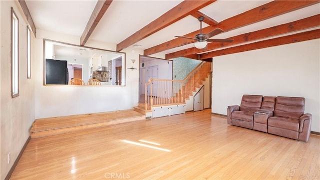 living area with ceiling fan, beam ceiling, stairway, and wood finished floors