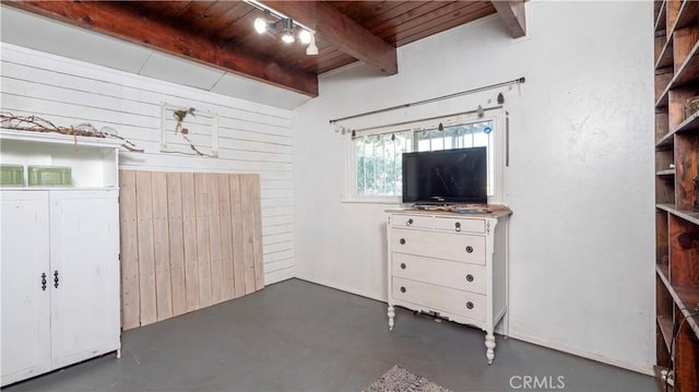 unfurnished bedroom featuring finished concrete flooring, wood walls, beamed ceiling, and wooden ceiling