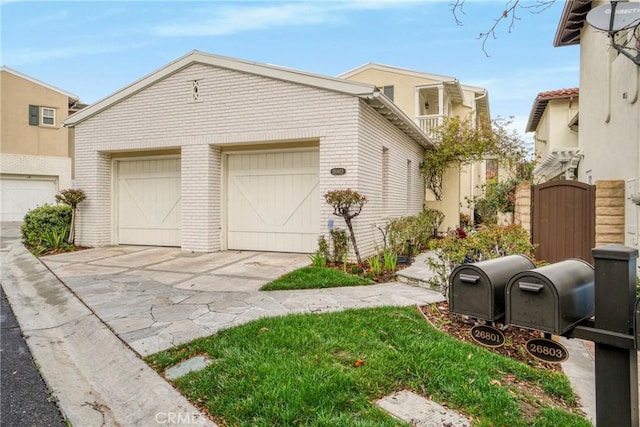 view of front of property with a gate, brick siding, an attached garage, and concrete driveway