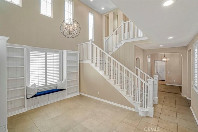 26803 Brookhollow Dr, Valencia, CA 91355 - stairs with a chandelier, a towering ceiling, arched walkways, baseboards, and tile patterned flooring