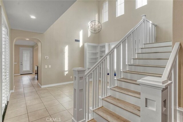 26803 Brookhollow Dr, Valencia, CA 91355 - stairs with tile patterned flooring, a towering ceiling, arched walkways, baseboards, and a chandelier