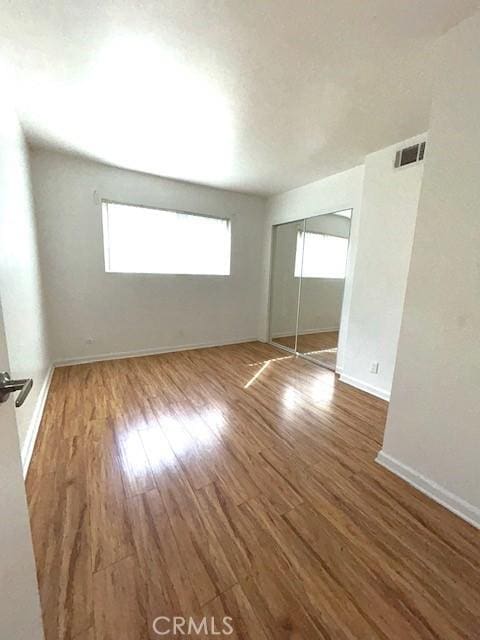 spare room with wood finished floors, visible vents, and baseboards