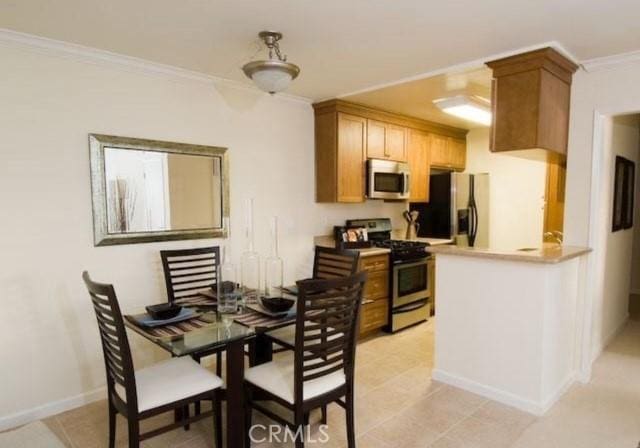 kitchen featuring stainless steel appliances, crown molding, a peninsula, and baseboards