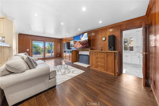 living room featuring wood walls, dark wood-type flooring, crown molding, and recessed lighting