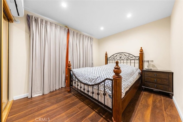 bedroom featuring recessed lighting, a wall mounted air conditioner, baseboards, and wood finished floors