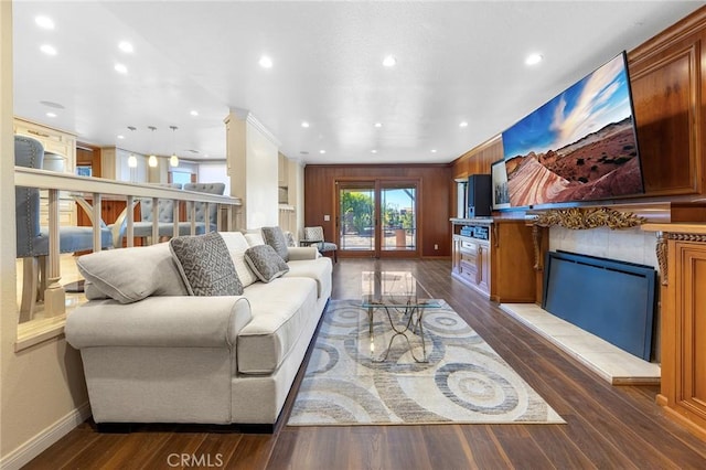 living area with dark wood-type flooring, recessed lighting, a fireplace with raised hearth, and baseboards