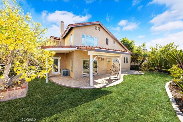 rear view of property featuring a tile roof, a chimney, a yard, central AC, and stucco siding