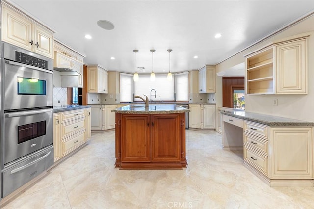 kitchen with a warming drawer, stainless steel appliances, cream cabinets, and a wealth of natural light