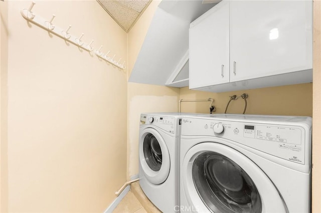 clothes washing area with cabinet space, light tile patterned floors, baseboards, and separate washer and dryer