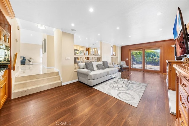 living area with dark wood-type flooring, recessed lighting, ornamental molding, and baseboards