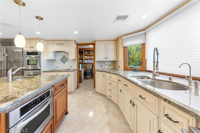 kitchen featuring appliances with stainless steel finishes, cream cabinetry, visible vents, and a sink