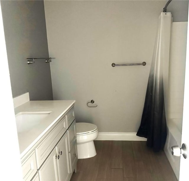 bathroom with curtained shower, vanity, baseboards, and wood finished floors