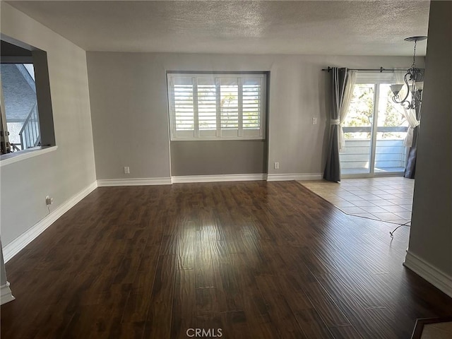 spare room with a textured ceiling, wood finished floors, and baseboards