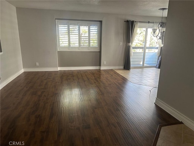 unfurnished room featuring a textured ceiling, wood finished floors, and baseboards