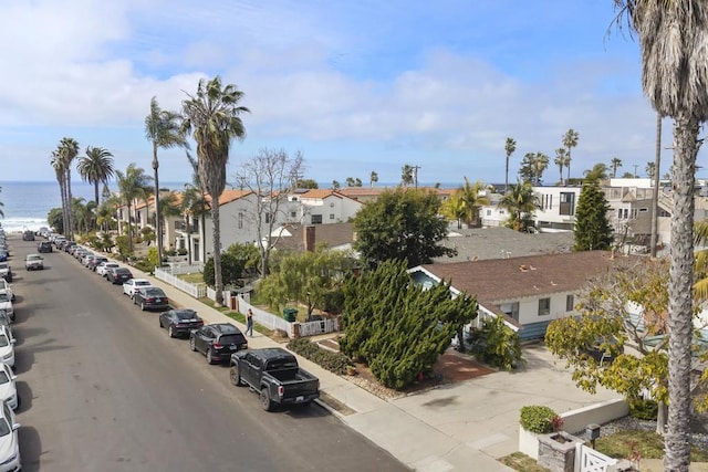 view of street with sidewalks, a water view, and a residential view