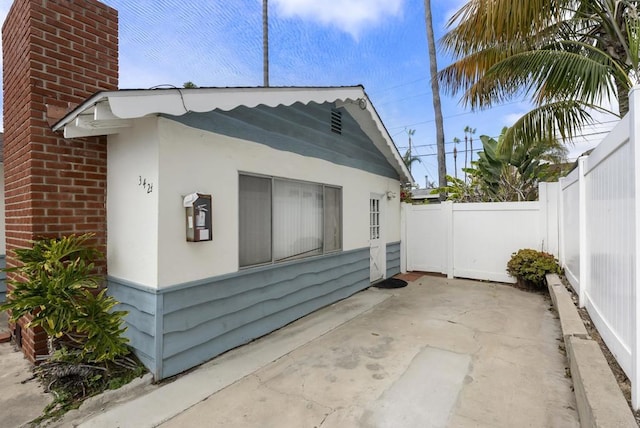 view of property exterior with a patio, fence, and stucco siding