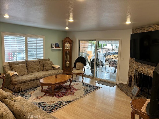 living room with recessed lighting, a textured ceiling, a large fireplace, and wood finished floors