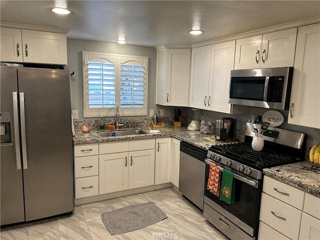 kitchen with white cabinets, stainless steel appliances, marble finish floor, and a sink