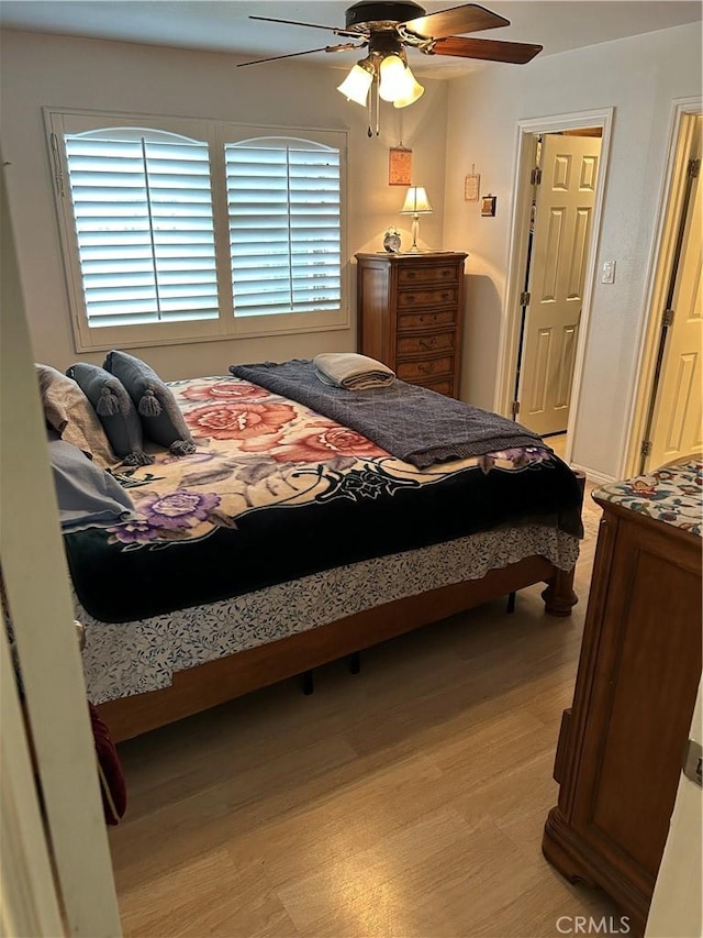 bedroom featuring multiple windows, a ceiling fan, and light wood-style floors