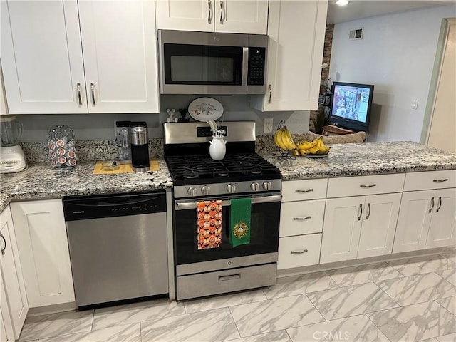 kitchen with visible vents, light stone counters, white cabinets, marble finish floor, and stainless steel appliances