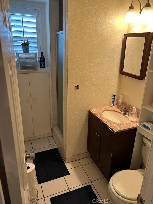 full bath featuring toilet, a stall shower, a textured wall, tile patterned floors, and vanity