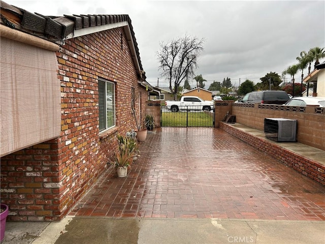 view of side of home featuring brick siding and fence