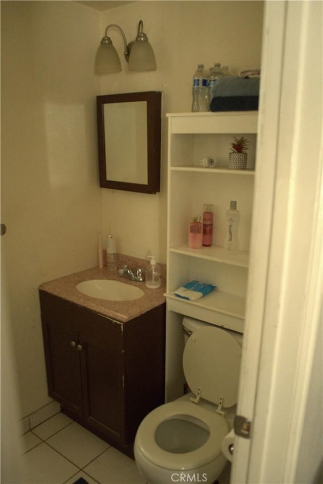 half bathroom featuring vanity, tile patterned floors, and toilet