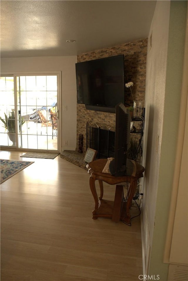 living area with a brick fireplace, wood finished floors, and a textured ceiling