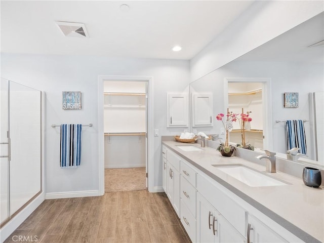 full bathroom featuring wood finished floors, a stall shower, a sink, and visible vents