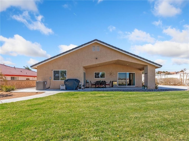 rear view of property with a patio, central AC unit, fence, a lawn, and stucco siding