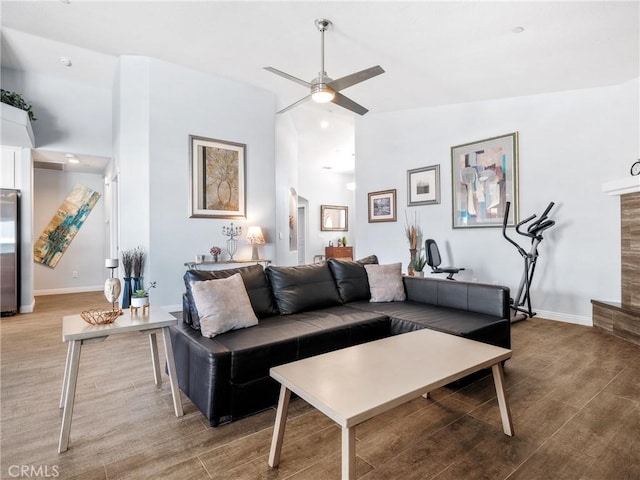 living room with ceiling fan, baseboards, and wood finished floors