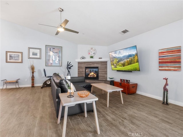 living room with baseboards, visible vents, wood finished floors, and a tile fireplace