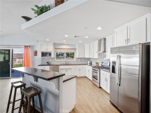 kitchen with wall chimney exhaust hood, appliances with stainless steel finishes, visible vents, and a healthy amount of sunlight