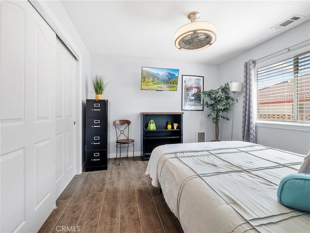 bedroom with dark wood-style floors, a closet, visible vents, and baseboards