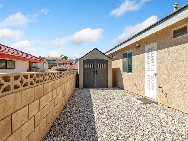 exterior space featuring stucco siding, an outdoor structure, fence, and a shed