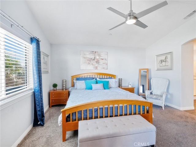 carpeted bedroom featuring arched walkways, lofted ceiling, visible vents, ceiling fan, and baseboards